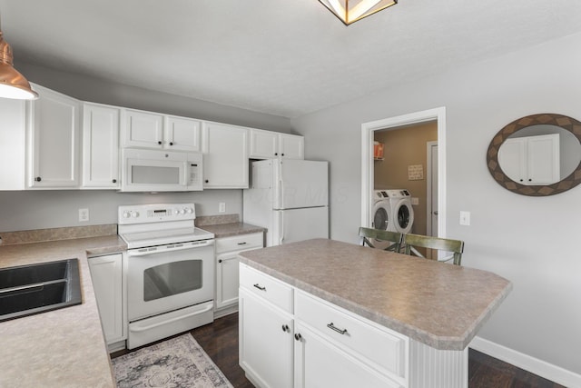 kitchen featuring white appliances, a kitchen island, washer and dryer, white cabinetry, and a sink