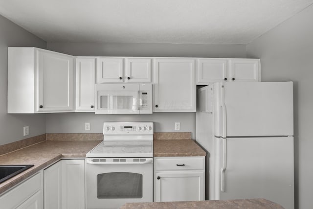 kitchen with dark countertops, white appliances, and white cabinetry