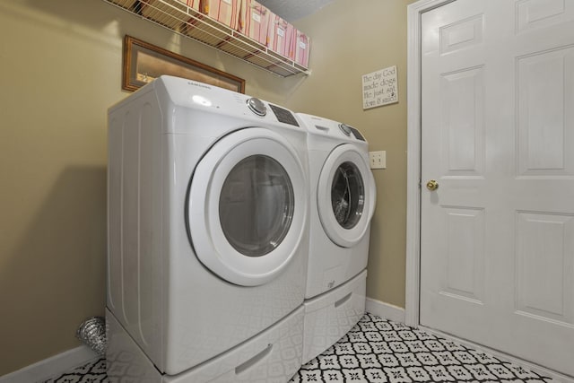 washroom featuring laundry area, baseboards, and washing machine and clothes dryer