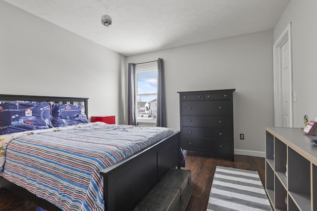 bedroom with a textured ceiling, dark wood finished floors, and baseboards