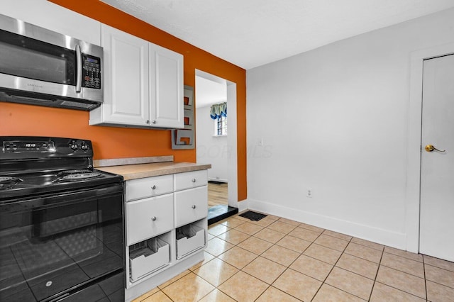 kitchen featuring light tile patterned flooring, white cabinets, and black range with electric cooktop