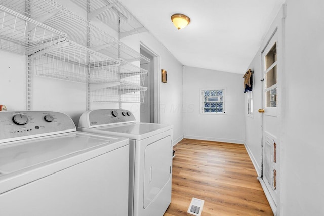 laundry room featuring washing machine and clothes dryer and light hardwood / wood-style floors