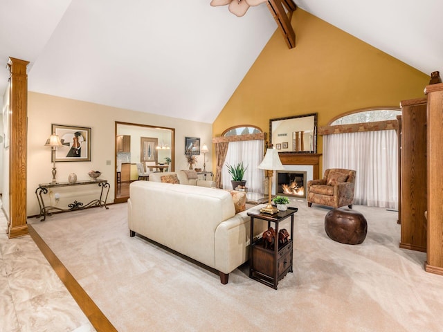 living room featuring high vaulted ceiling, light colored carpet, beam ceiling, a glass covered fireplace, and ornate columns