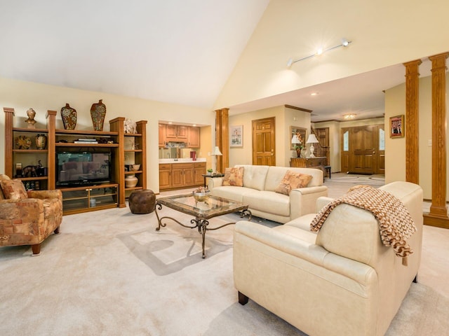 living area featuring high vaulted ceiling, decorative columns, and light colored carpet