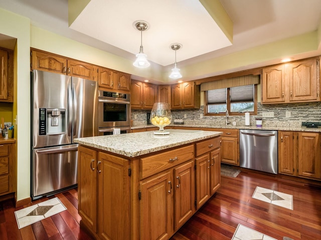 kitchen with stainless steel appliances, a kitchen island, dark wood-style floors, brown cabinetry, and decorative light fixtures