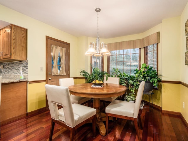 dining room featuring baseboards, dark wood-type flooring, and a notable chandelier