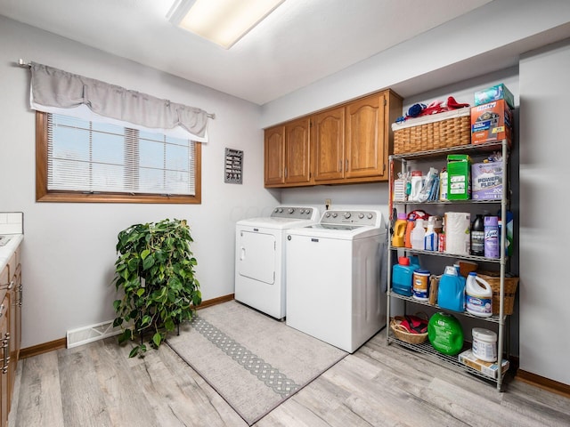 clothes washing area with separate washer and dryer, visible vents, baseboards, light wood-style floors, and cabinet space