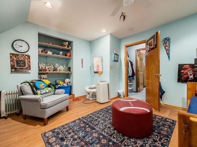 living area featuring baseboards, a ceiling fan, radiator, wood finished floors, and recessed lighting