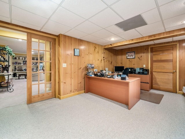 office space featuring a paneled ceiling, wood walls, and light colored carpet