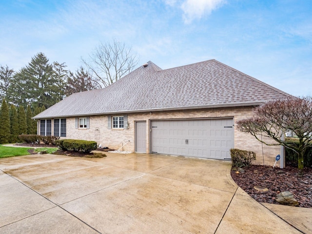 view of front of home with concrete driveway, brick siding, and roof with shingles