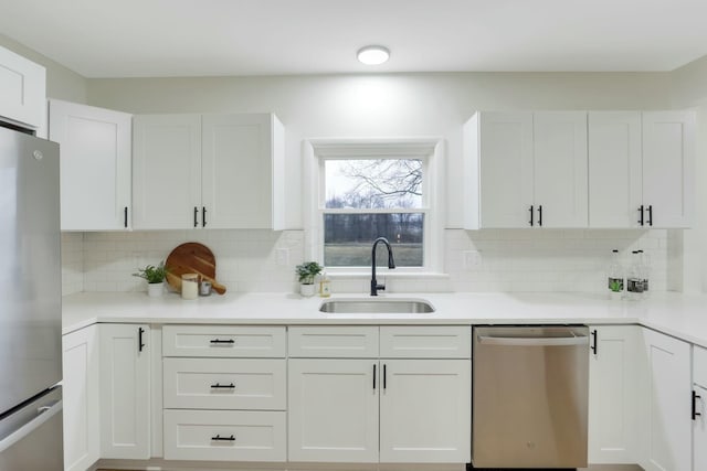 kitchen with white cabinetry, appliances with stainless steel finishes, sink, and backsplash