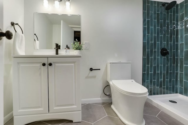 bathroom featuring tile patterned flooring, vanity, tiled shower, and toilet