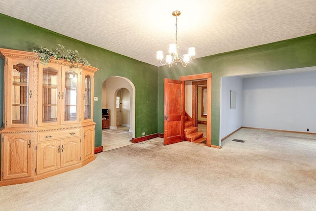 dining space with light carpet, a textured ceiling, and an inviting chandelier