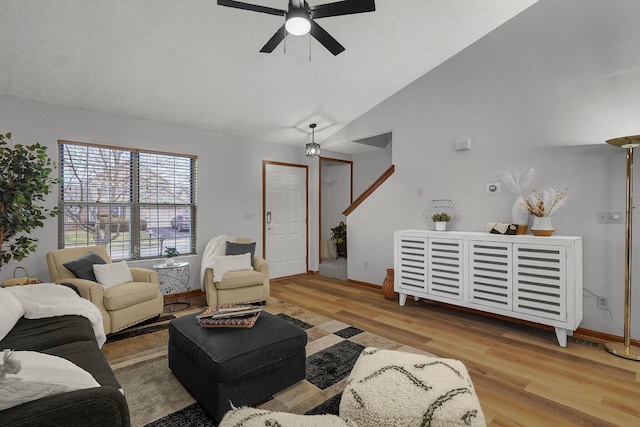 living room with ceiling fan, lofted ceiling, a textured ceiling, and light hardwood / wood-style floors