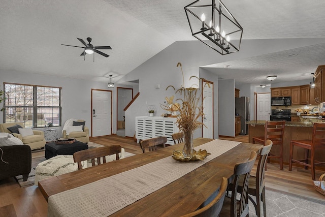 dining space with lofted ceiling, ceiling fan, a textured ceiling, and light wood-type flooring