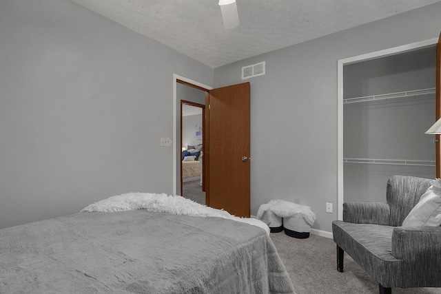 carpeted bedroom with ceiling fan, a closet, and a textured ceiling