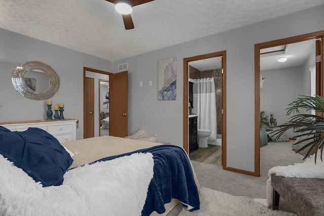 bedroom featuring ceiling fan, connected bathroom, light carpet, and a textured ceiling