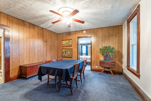 dining room with plenty of natural light, a textured ceiling, and dark colored carpet