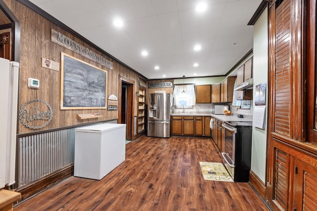 kitchen with sink, stainless steel appliances, dark hardwood / wood-style floors, ornamental molding, and wood walls