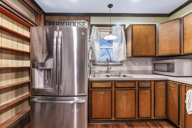 kitchen featuring dark wood-type flooring, sink, crown molding, hanging light fixtures, and stainless steel appliances