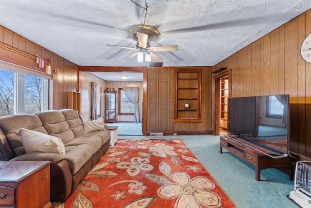 living room with built in shelves, light colored carpet, a textured ceiling, and wood walls