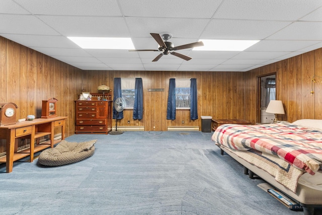 carpeted bedroom with a baseboard radiator, wooden walls, and ceiling fan