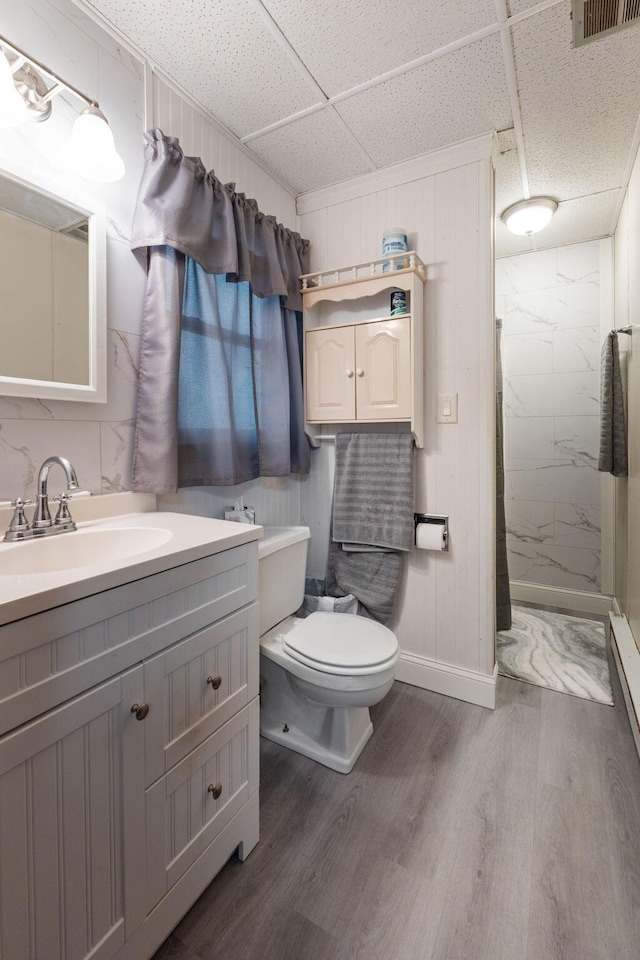 bathroom featuring hardwood / wood-style flooring, a paneled ceiling, vanity, a shower, and toilet