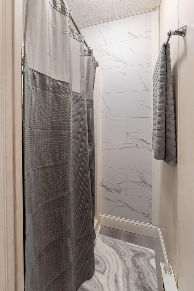 bathroom with wood-type flooring, a paneled ceiling, and walk in shower