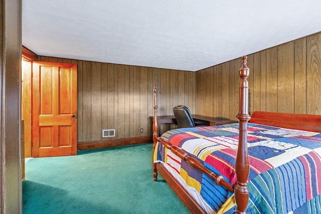 carpeted bedroom featuring wooden walls and a textured ceiling