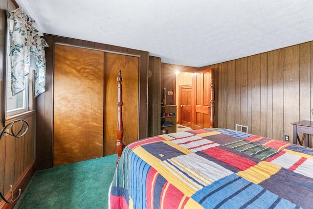 bedroom with carpet floors, a textured ceiling, and wooden walls