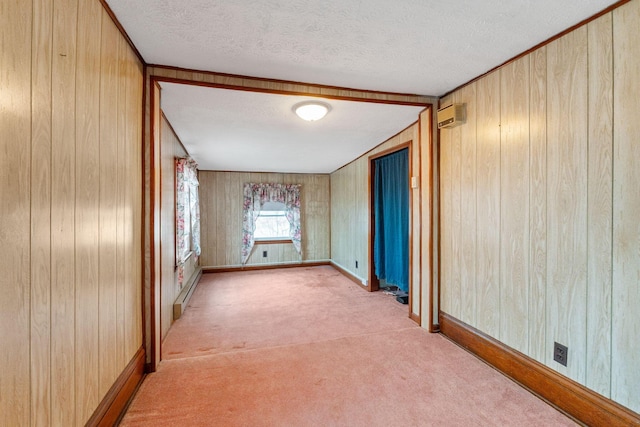 carpeted spare room featuring an AC wall unit, a textured ceiling, and wood walls