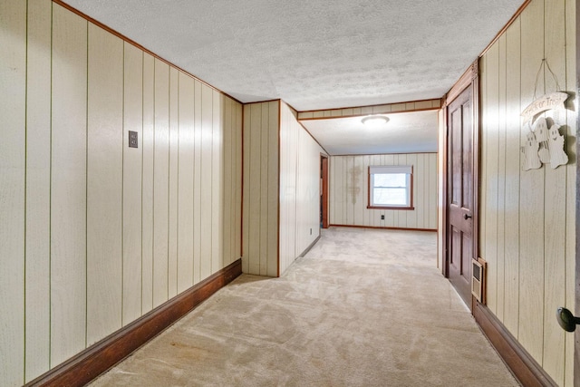 hallway with light colored carpet and a textured ceiling