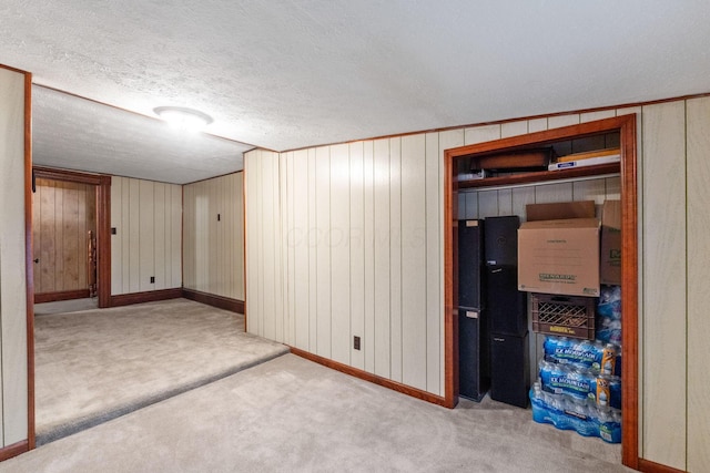 basement with wooden walls, light carpet, and a textured ceiling