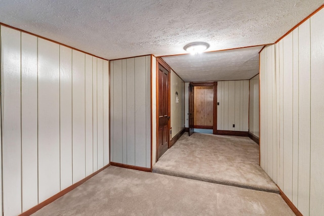 corridor featuring light carpet, a textured ceiling, and wood walls