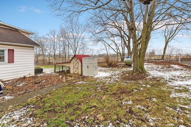 yard layered in snow with central air condition unit and a storage unit