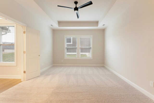 carpeted empty room featuring a raised ceiling and ceiling fan