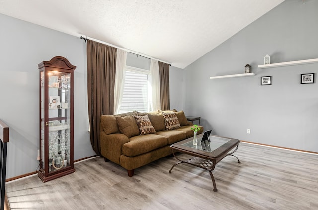 living area with light wood-style floors, baseboards, vaulted ceiling, and a textured ceiling