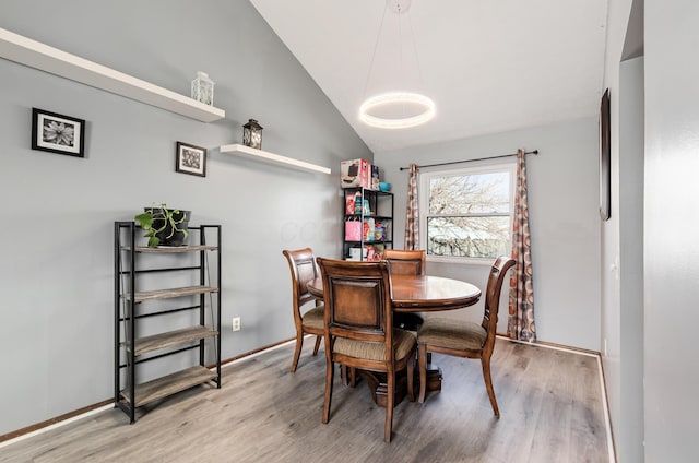 dining area featuring vaulted ceiling, baseboards, and wood finished floors