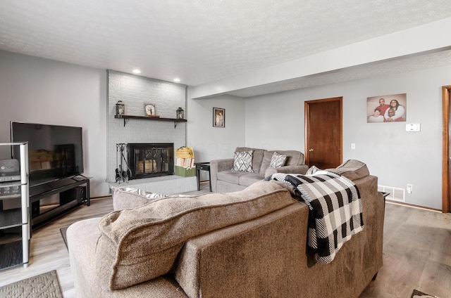 living room featuring light wood-type flooring, visible vents, and a textured ceiling