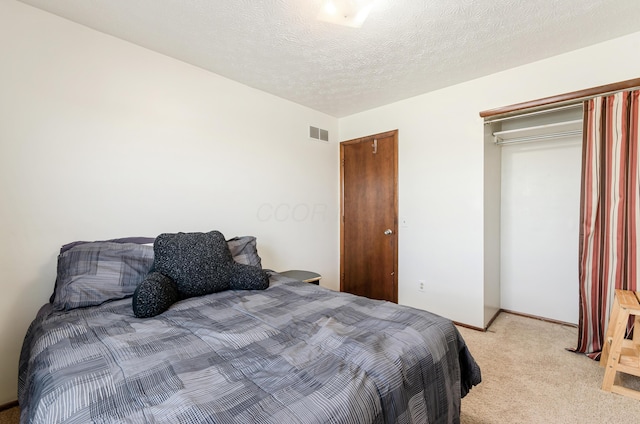 bedroom with visible vents, light carpet, and a textured ceiling