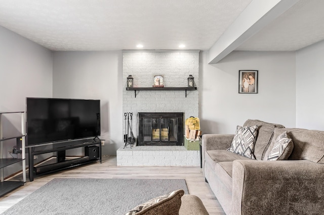 living room with a textured ceiling, a fireplace, wood finished floors, and recessed lighting