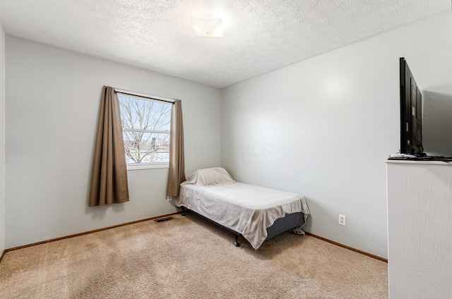 bedroom with a textured ceiling, carpet floors, visible vents, and baseboards