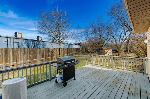 deck featuring a storage shed, a fenced backyard, a grill, a yard, and an outdoor structure