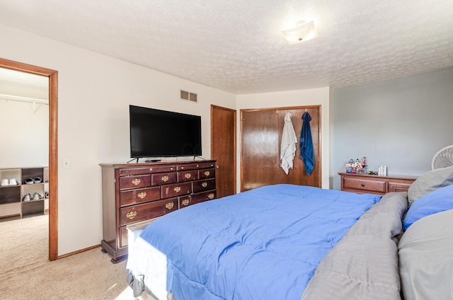 carpeted bedroom featuring baseboards, a textured ceiling, visible vents, and a closet