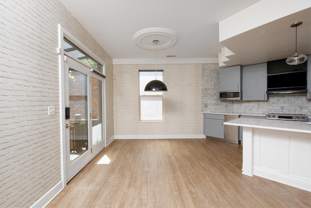 113 E Mithoff St, Columbus, OH 43206 - kitchen with gray cabinetry, light countertops, light wood-style flooring, stainless steel microwave, and brick wall