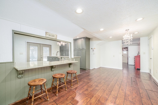 kitchen featuring a kitchen bar, french doors, gray cabinets, dark wood-style flooring, and a peninsula