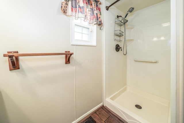 full bathroom featuring baseboards, wood finished floors, and a stall shower