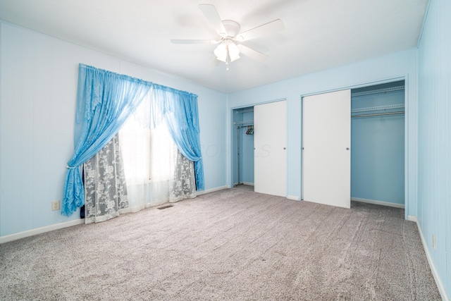 unfurnished bedroom featuring a ceiling fan, carpet flooring, and multiple closets