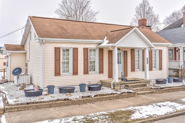 bungalow with roof with shingles and a chimney