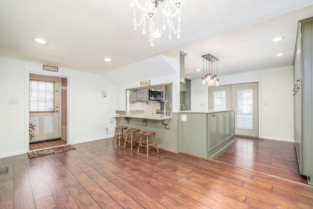 kitchen with dark wood-style floors, stainless steel microwave, plenty of natural light, a chandelier, and green cabinets